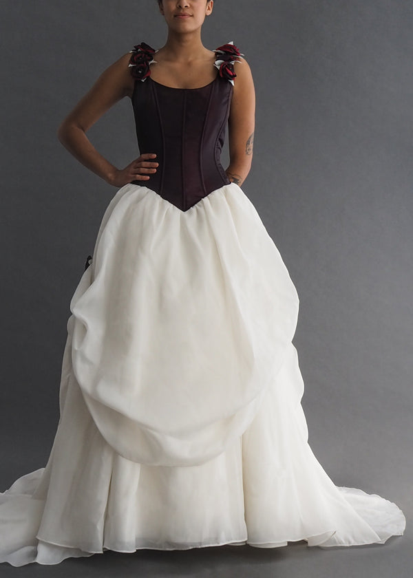 IAN STUART - Snow White bridal gown Iridescent burgundy corseted bodice, pointing to a strategically gathered, off-white ballgown skirt, trussed up with burgundy rosettes on flounces and straps