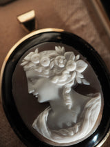 Exquisite vintage shell cameo with onyx surround and set in 14k gold. This is a rare left-facing profile cameo with delicately hand-carved botanical wreath crown - dating to approximately the early mid century. Piece features retractible bail that leaves pendant flush when being worn as brooch.