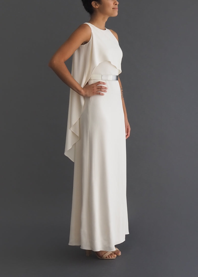 Halston sleek column bridal gown with asymmetrical cape and removable metal belt.