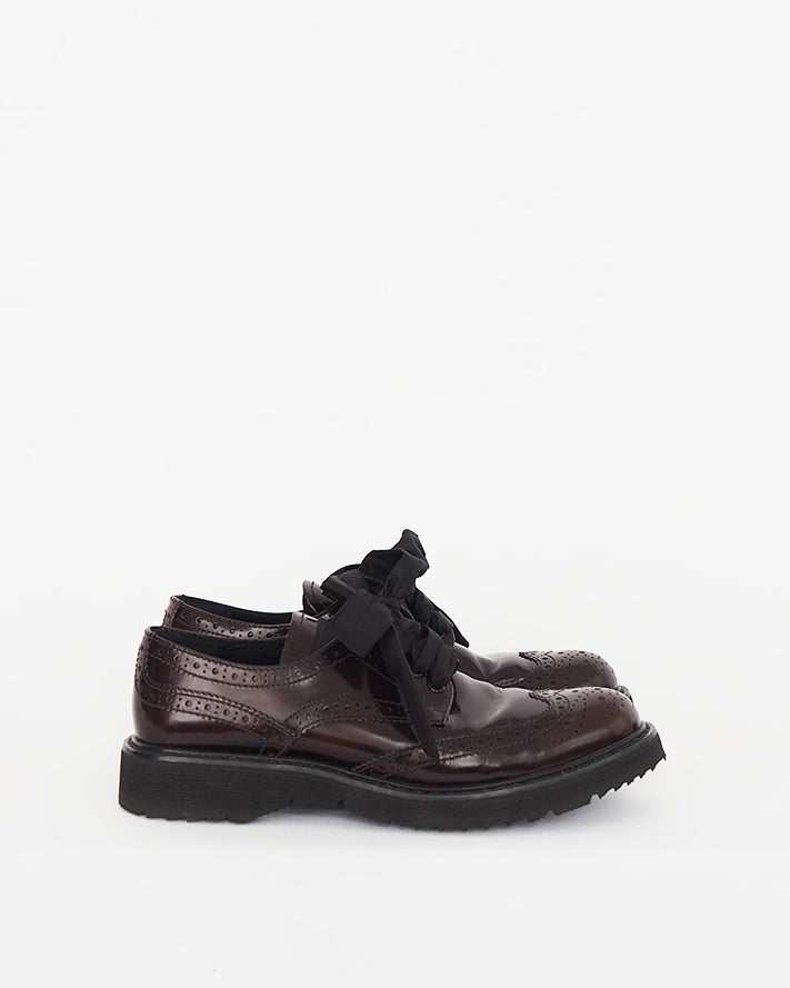 Prada oxblood brogue style shoe with traditional perforated leather uppers, taffeta ribbon lacing and heavy tread rubber sole.