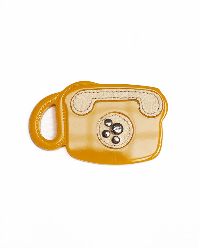 PRADA TELEPHONE BROOCH Abstracted telephone shape yellow resin base with leather and metal "rotary" detailing.