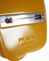 PRADA TELEPHONE BROOCH Abstracted telephone shape yellow resin base with leather and metal "rotary" detailing.