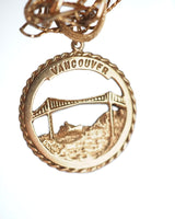 10K VANCOUVER CHARM Vintage round charm in 10k yellow gold, featuring a delicate Lions Gate Bridge depiction and cruise ship.