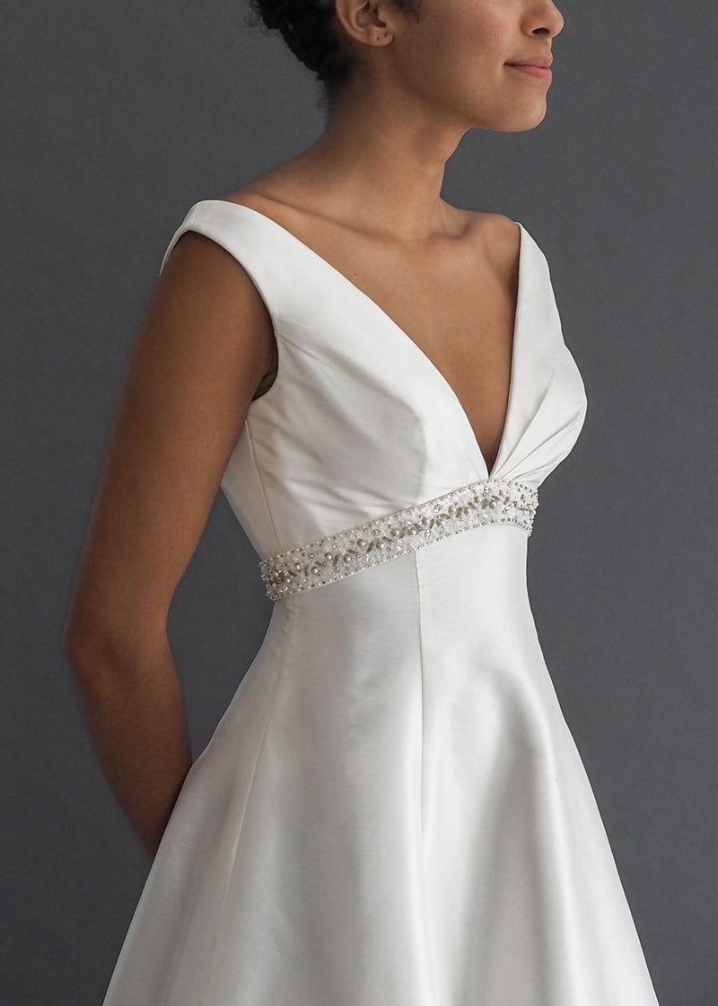 Venus International Designers A-line ball gown in off white with plunging v-neck, beaded empire waist detailing and striking train.