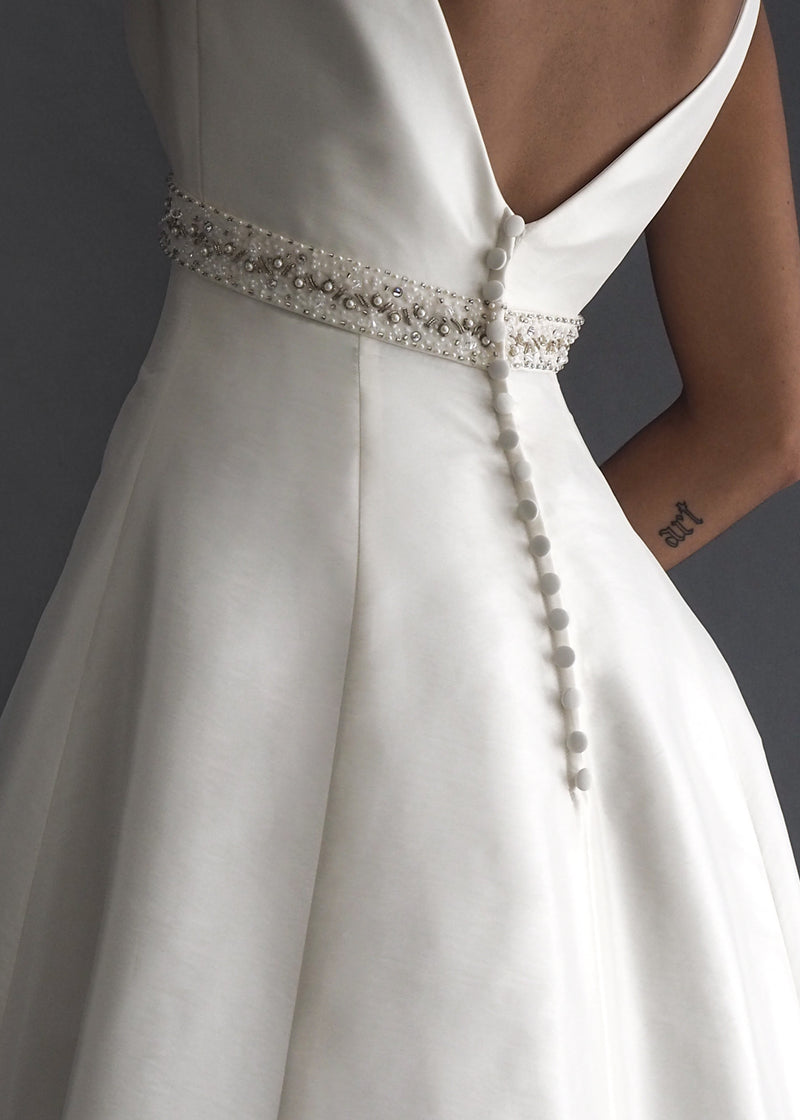 Venus International Designers A-line ball gown in off white with plunging v-neck, beaded empire waist detailing and striking train.