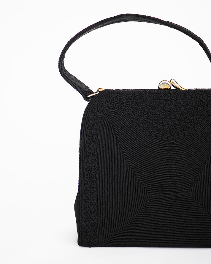 Vintage black corde top handle purse featuring abstract tone on tone pattern and asymmetrical closure and mini change purse.