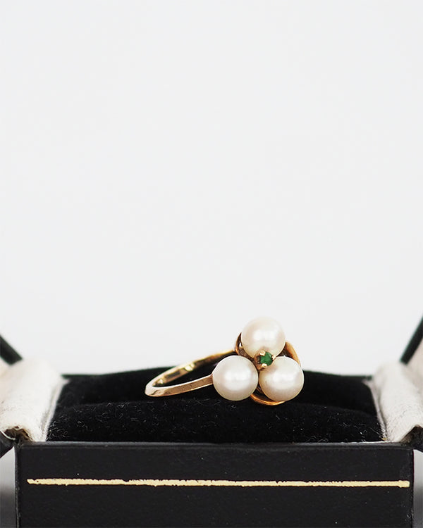 10k gold knotted ring set with three cultured pearls and an emerald chip.